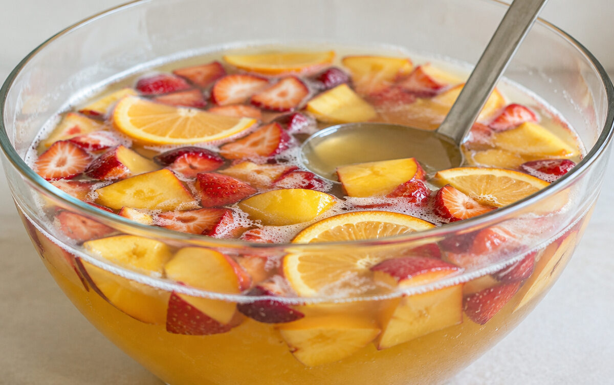 Bierbowle mit Erdbeeren, Pfirsichen und Orangenscheiben in einer großen Glasschüssel