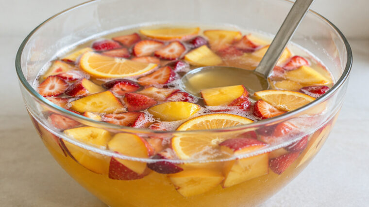 Bierbowle mit Erdbeeren, Pfirsichen und Orangenscheiben in einer großen Glasschüssel