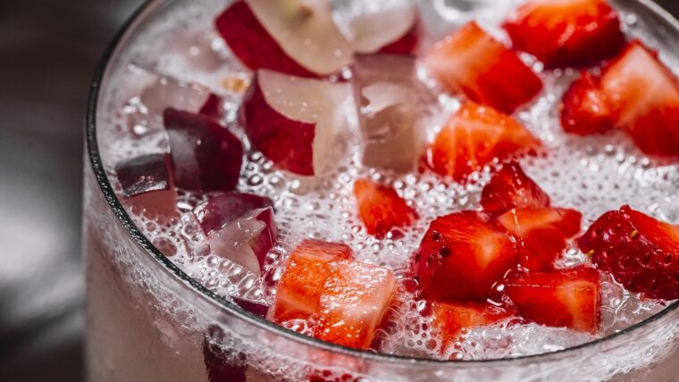 Erdbeerbowle mit Erdbeerstücken und Eis in einem großen Glas