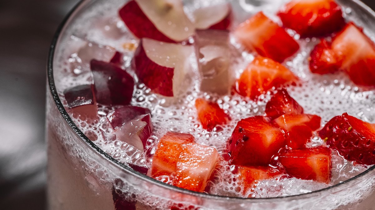 Erdbeerbowle mit Erdbeerstücken und Eis in einem großen Glas