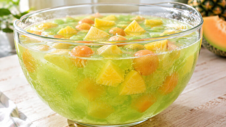 Midori-Melonenbowle mit Ananasstücken und Cantaloupe-Melone in einer großen Glasschüssel