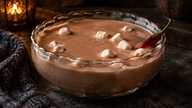 Cremige Schoko-Chili-Bowle mit Licor 43, Mini-Marshmallows und roter Chilischote in einer Glasschüssel